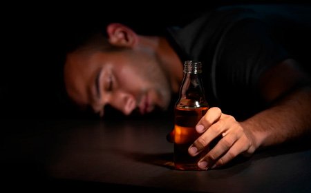 Мужчина лежит на полу держа в руках бутылку