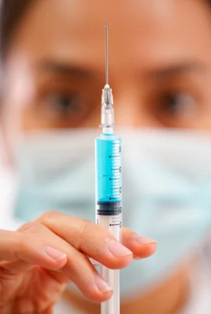 Шприц на фоне врача